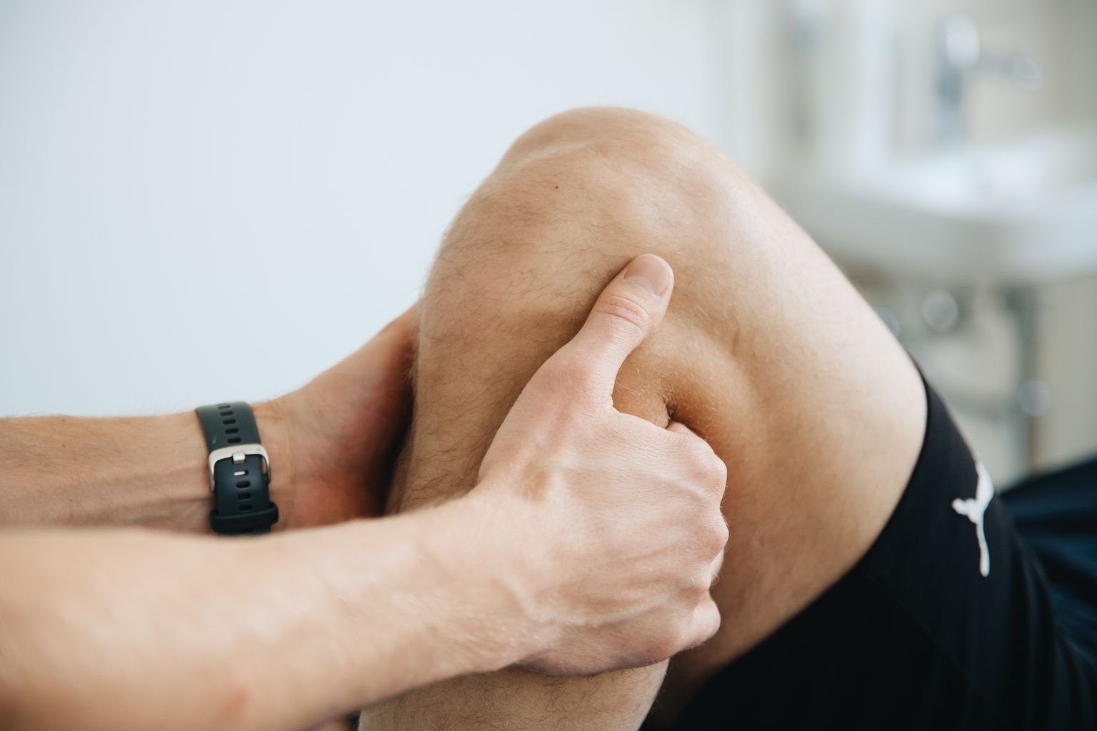 Physiotherapist assessing a patient with inner knee pain in a clinical setting