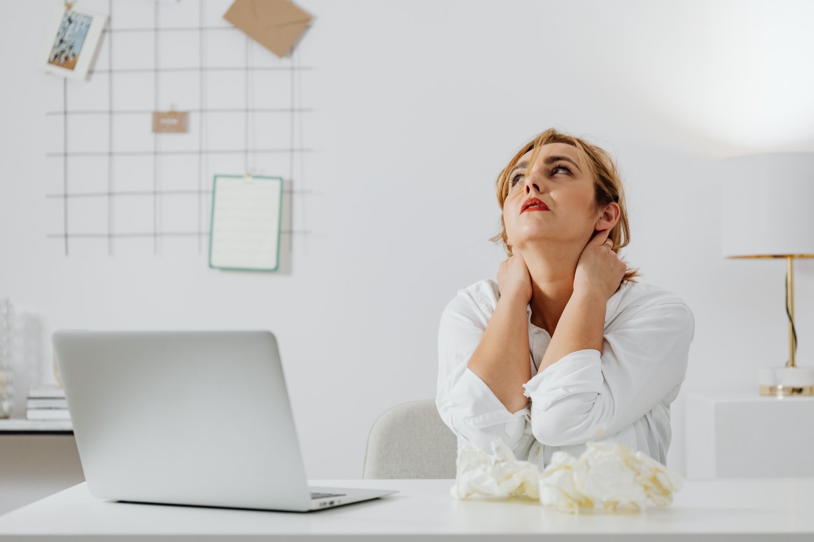 Woman rubbing her neck at a desk due to headache at base of skull