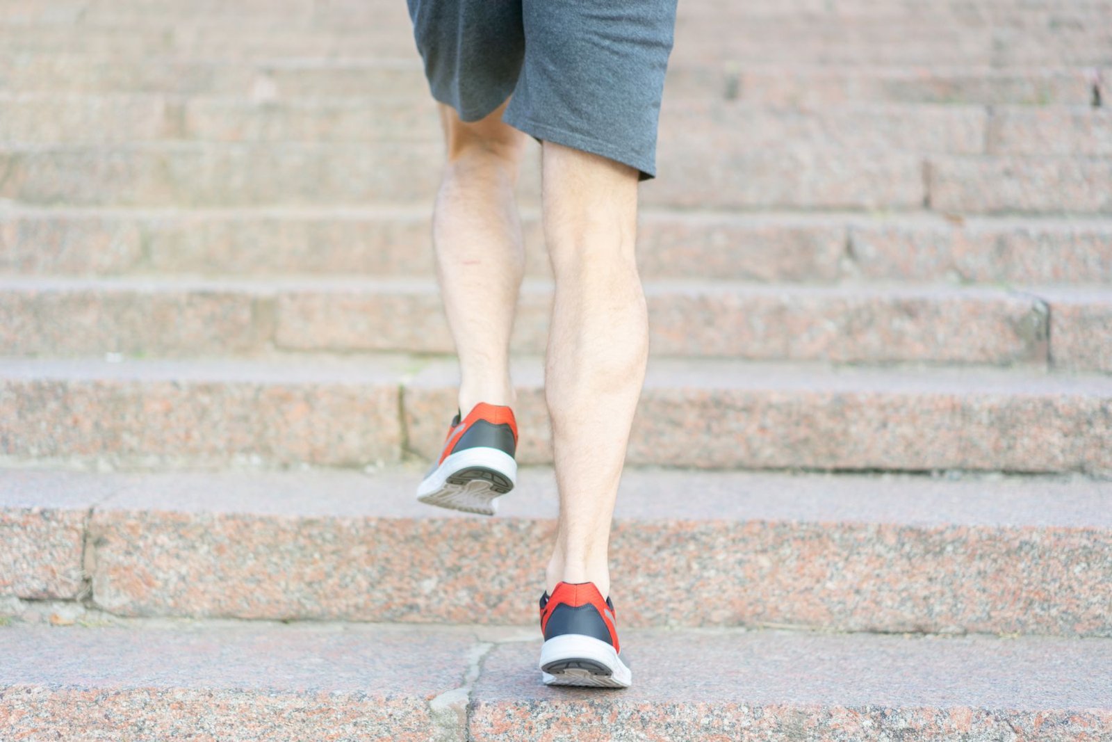 Person climbing outdoor stone steps, illustrating the loaded movement behind knee pain going up stairs