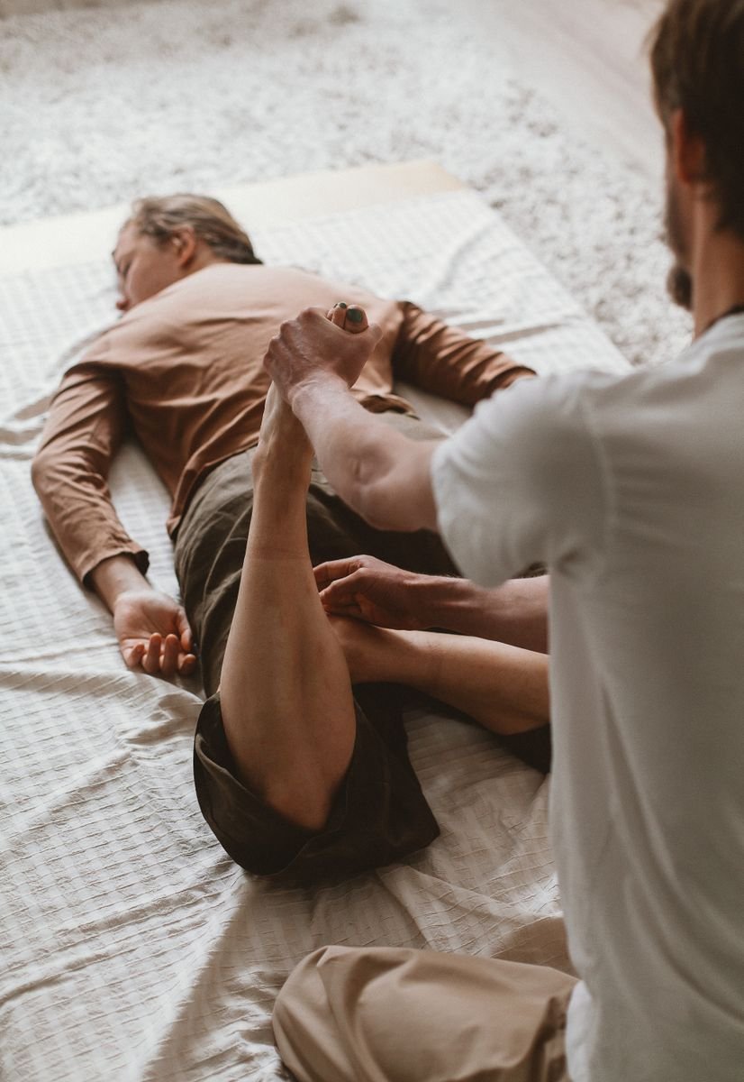 A therapist guiding a client through stretching as part of a staged MCL physical therapy exercises programme.