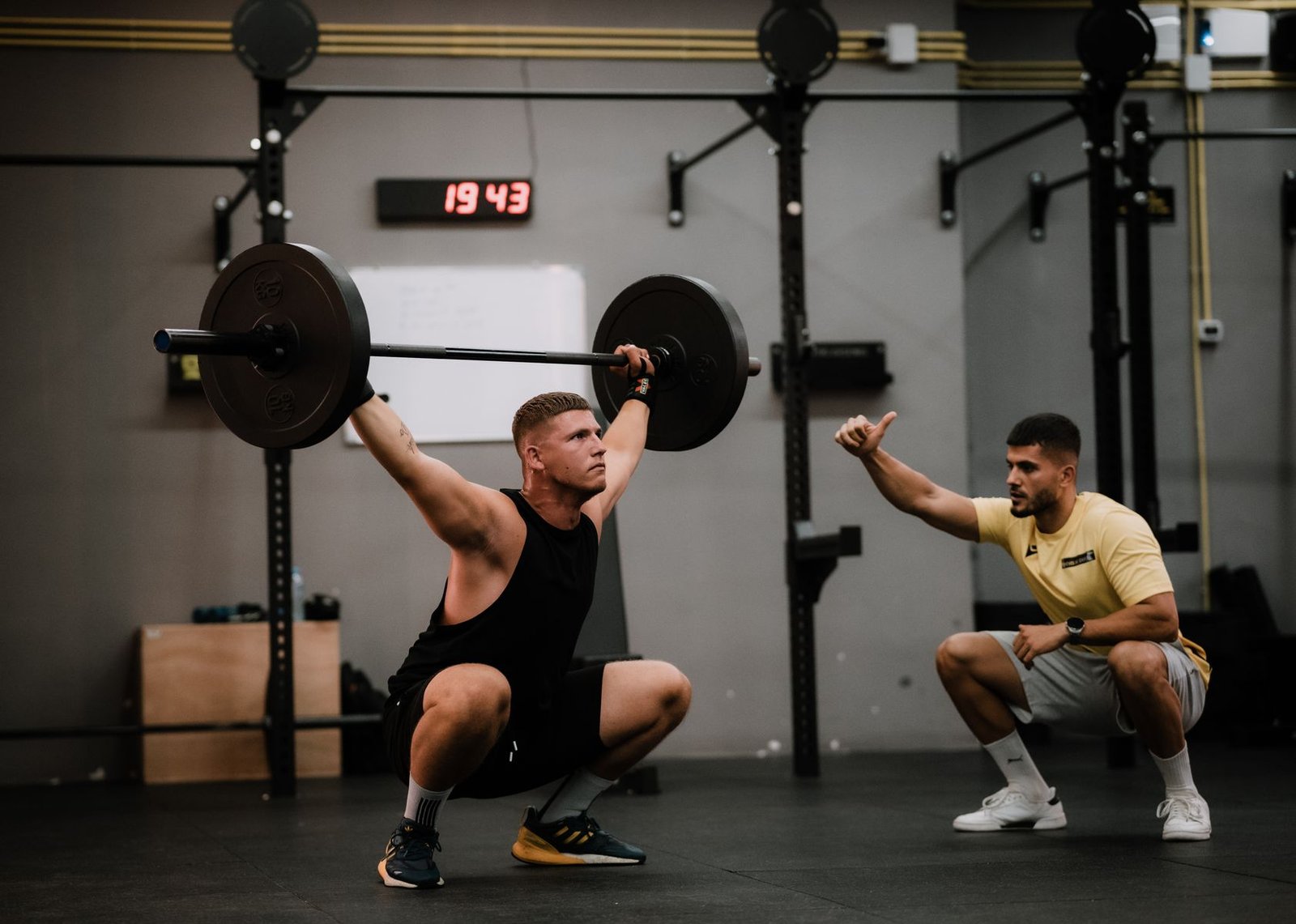 Coach checking squat technique with a lifter, relevant to lower back pain after squats