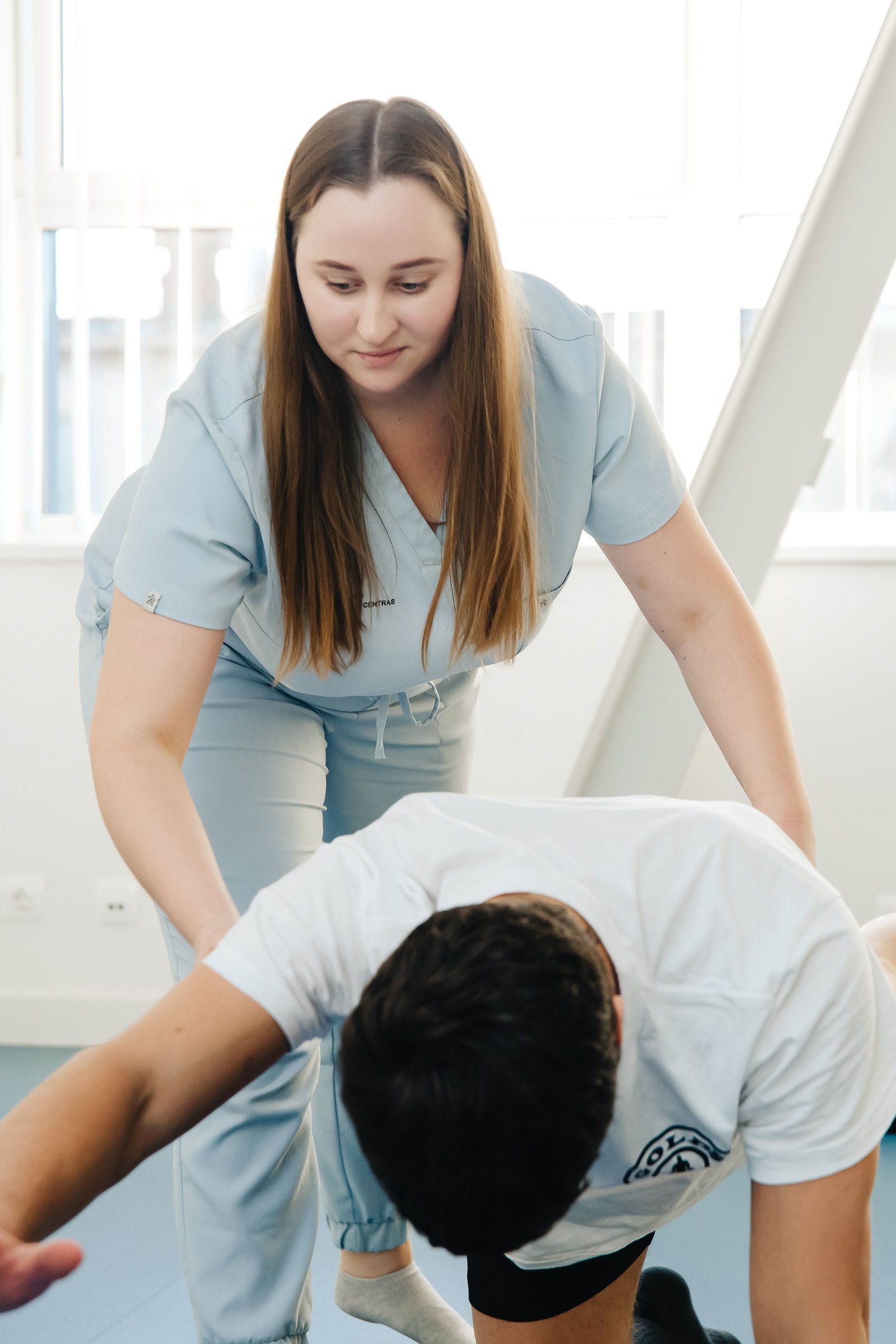 Physiotherapist guiding a patient through controlled physical therapy while in pain