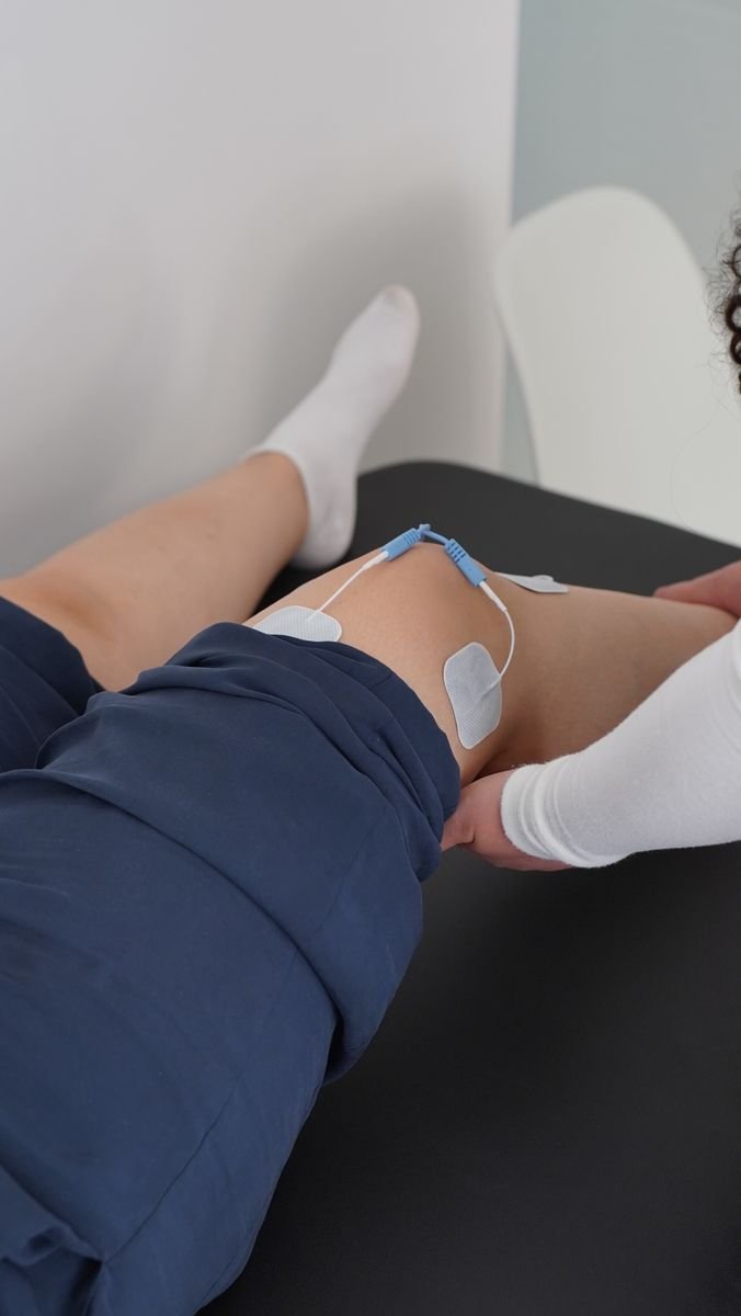 A physiotherapist supporting a client's guided knee rehabilitation exercises during recovery from swelling after knee replacement.
