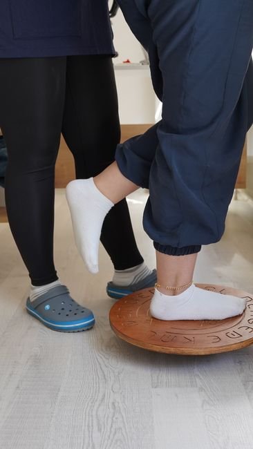 Physiotherapist guiding a progressive balance exercise as part of plantar tendonitis rehab