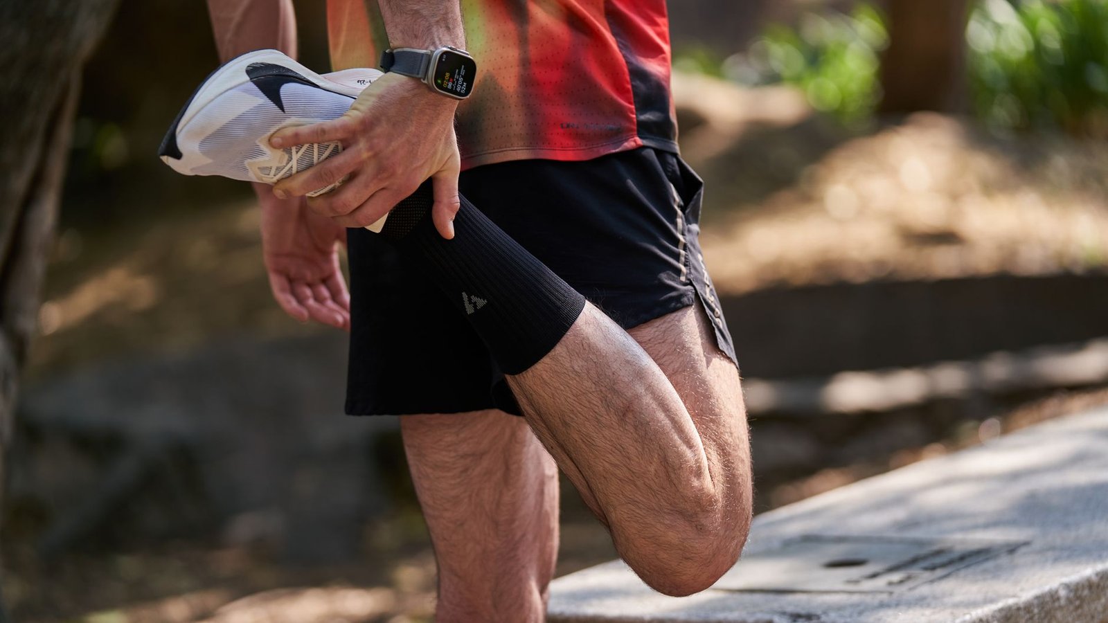 Runner doing post-marathon recovery stretching after finishing a race