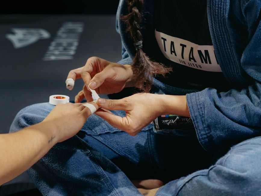 Grappler taping fingers before training to protect jiu jitsu fingers from chronic strain