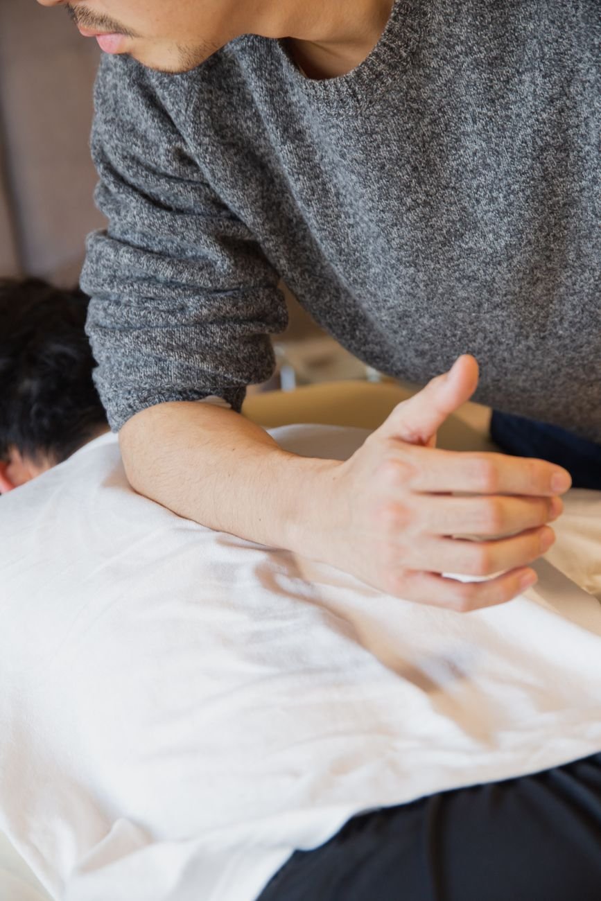 Physiotherapist assessing a client's upper back muscles for signs of a rhomboid strain