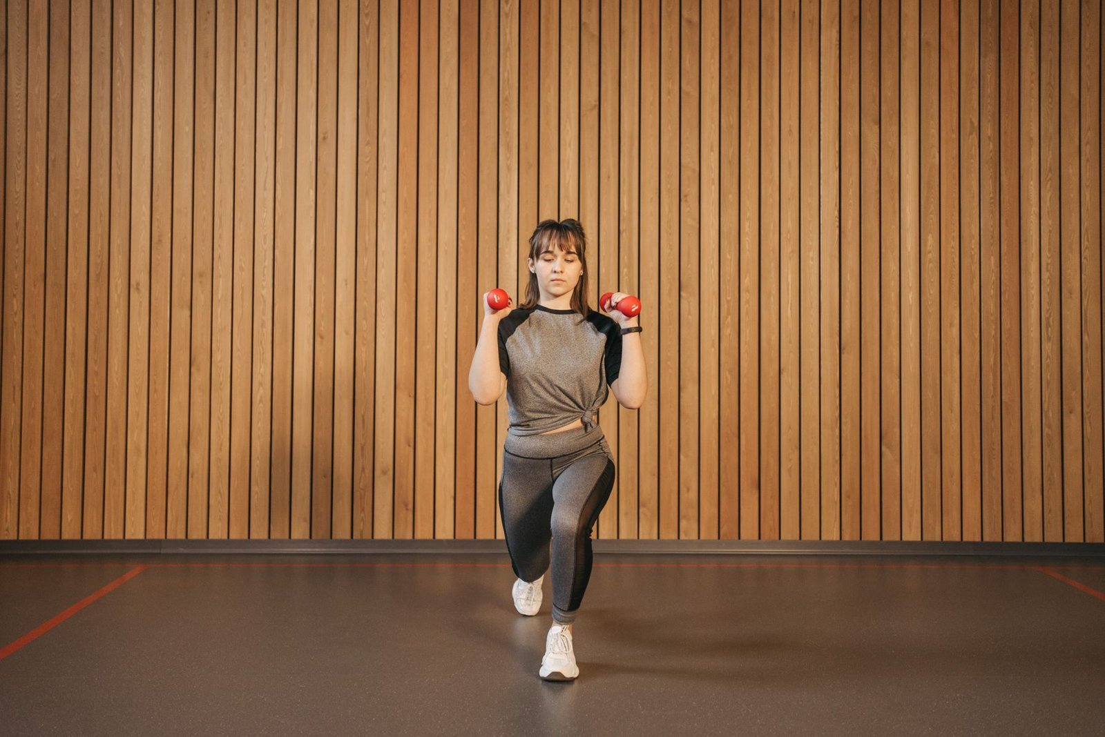 Woman performing a lunge with dumbbells, a later-stage mcl rehab exercises example