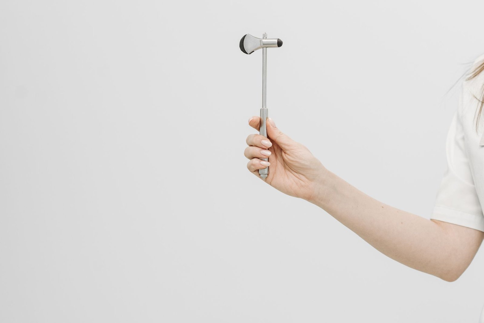 Healthcare professional holding a reflex hammer, part of assessing sciatica numbness on top of foot