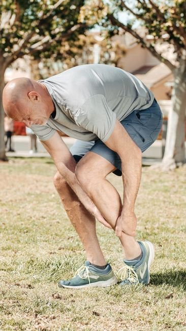 A runner holding their shin, illustrating the location a stress fracture self-check should focus on.