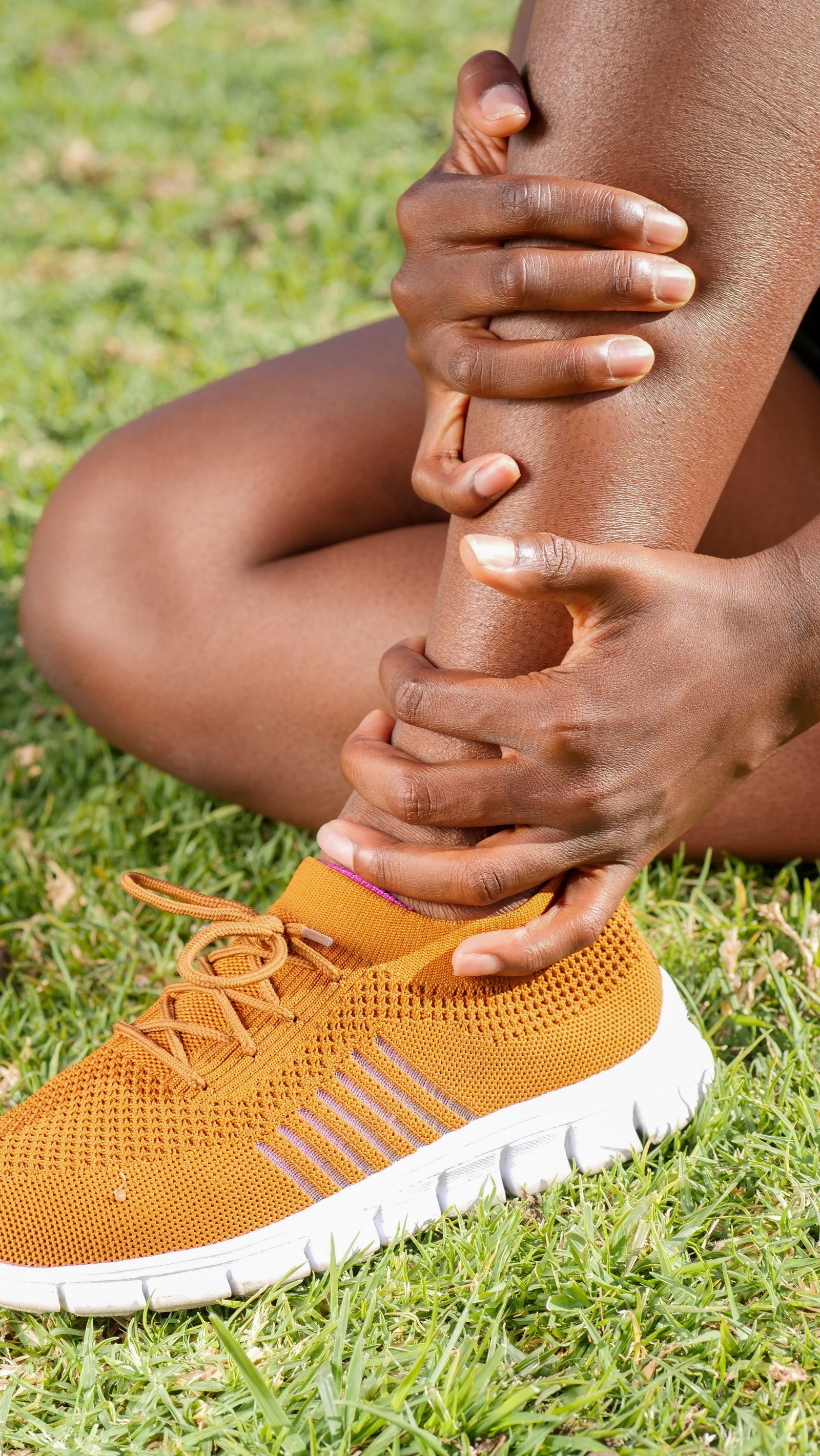 Person holding their ankle, illustrating the signs of a stress fracture ankle