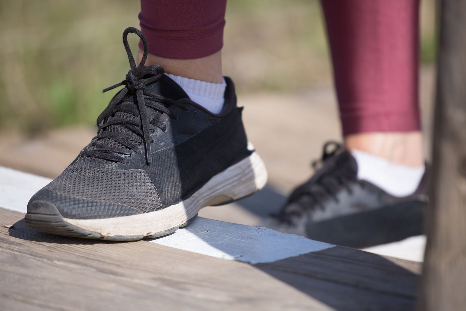 Person stepping onto a raised step edge, a movement pattern used in achilles tendon exercises like heel drops