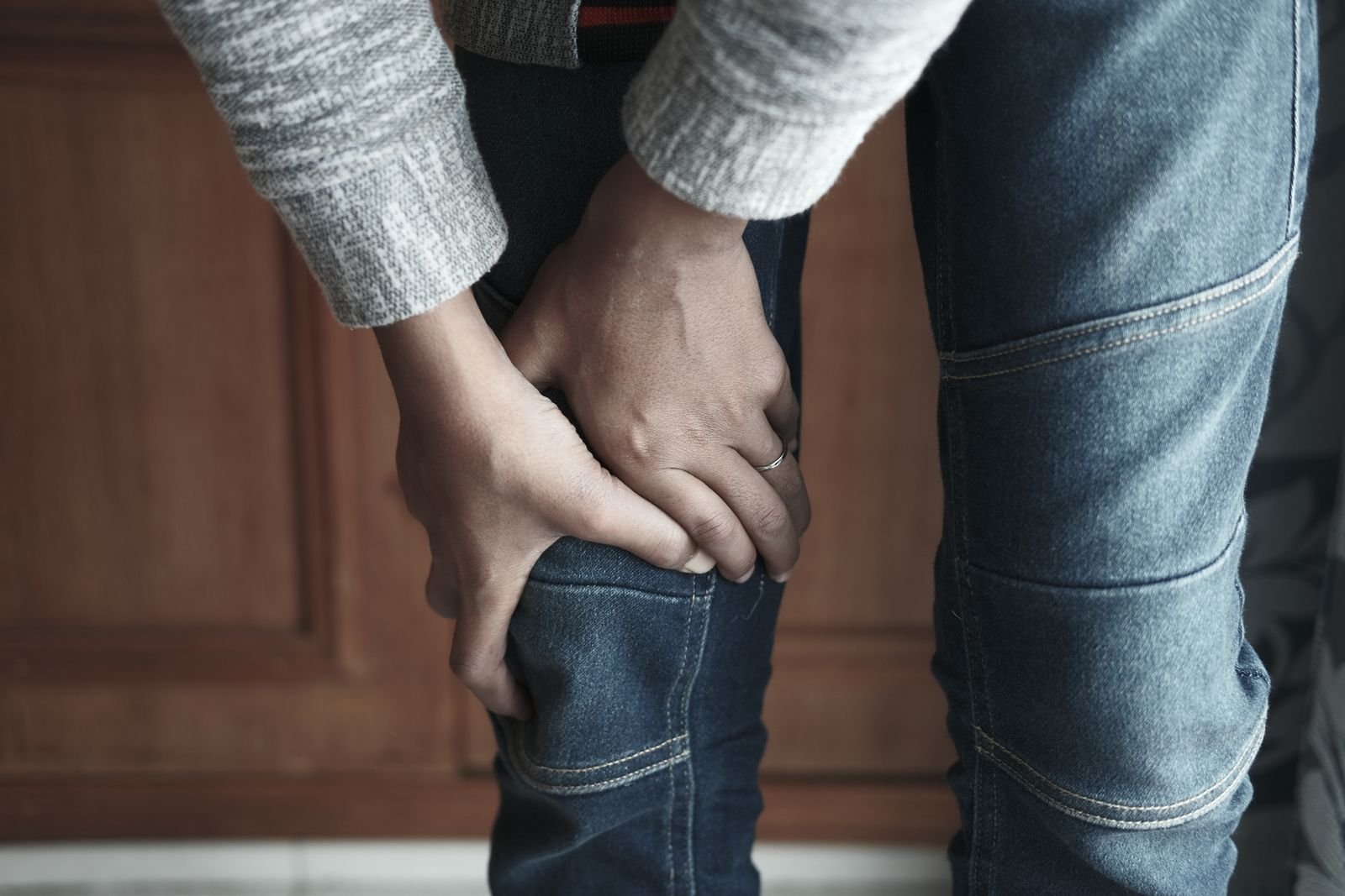 A person holding their sore knee, a sign that an MCL knee injury may need a proper assessment.