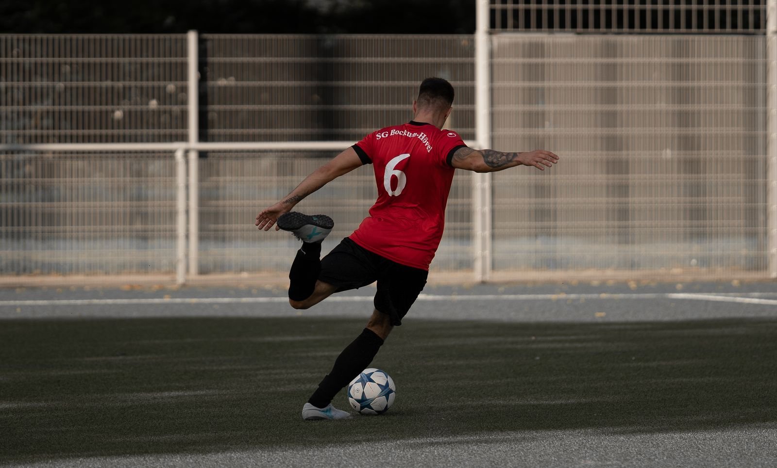 A footballer kicking a ball in training, the kind of high-speed demand groin strain rehab must prepare the muscle for.