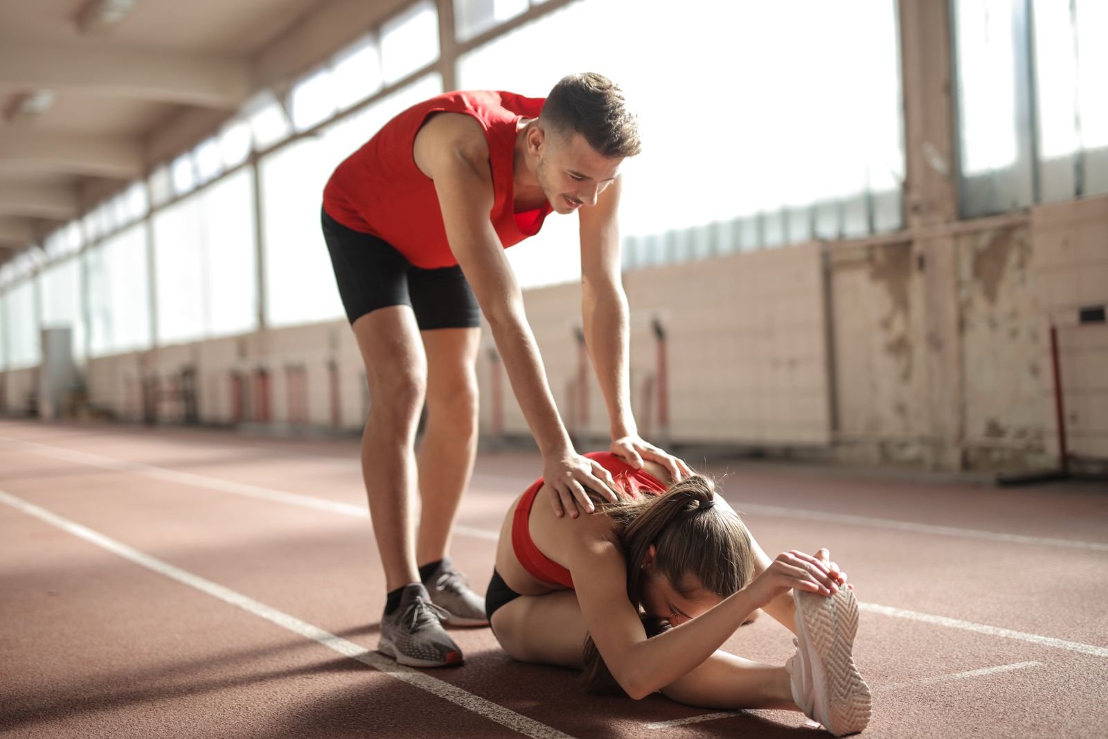 An athlete stretching their hamstring on a sports field during the later stages of hamstring strain recovery.