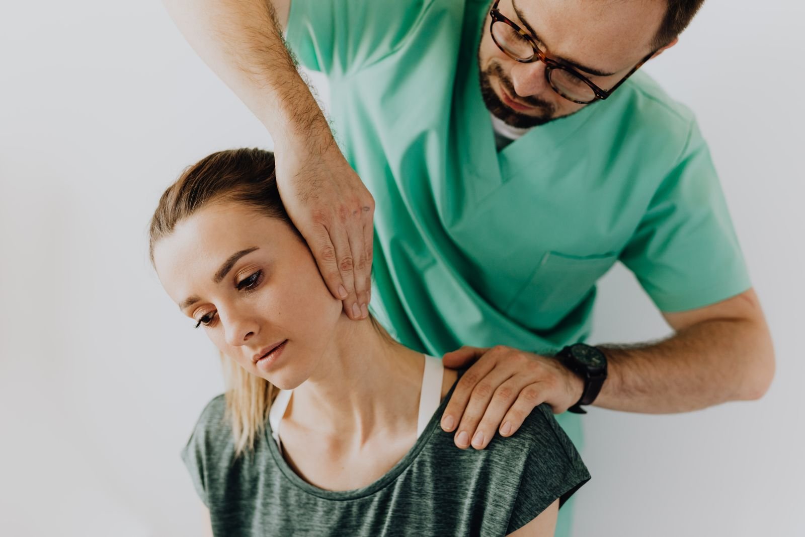 A therapist gently stretching a patient's neck and upper shoulder muscles to ease pain in shoulder and neck.