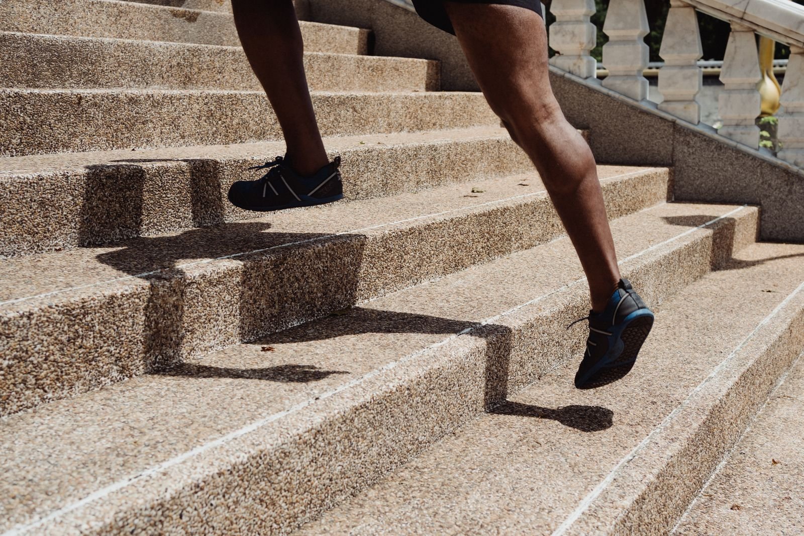 Close-up of a runner's calves driving up stone steps, the kind of lower-leg strength that exercises to prevent shin splints aim to build.