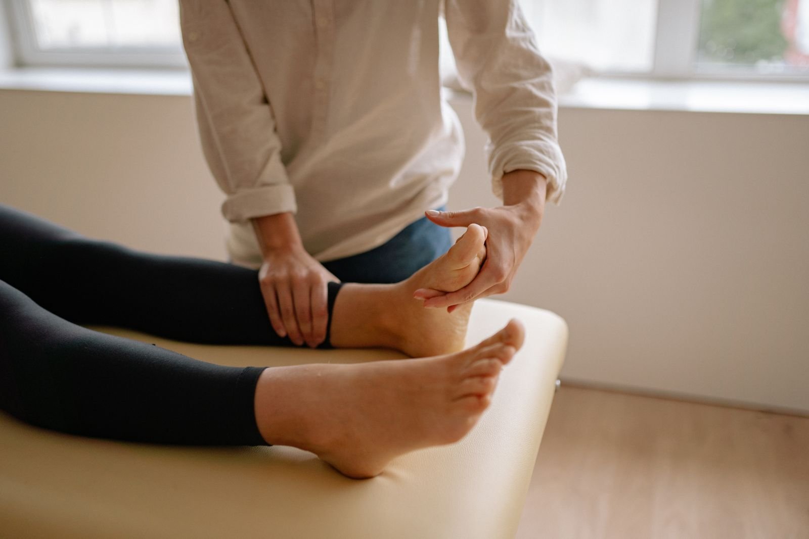 A therapist examining a patient's heel and arch while planning the best stretches for plantar fasciitis as part of a rehab plan.