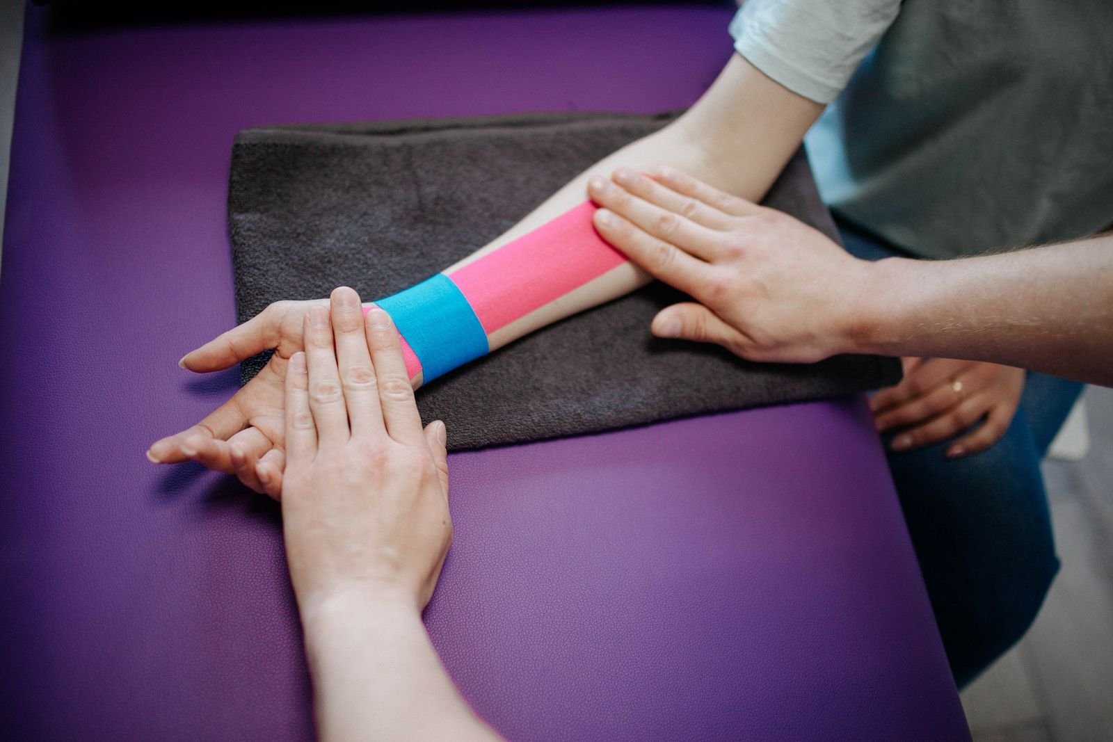 A therapist applying kinesiology tape, showing that technique matters more than the Rocktape vs KT Tape brand choice.